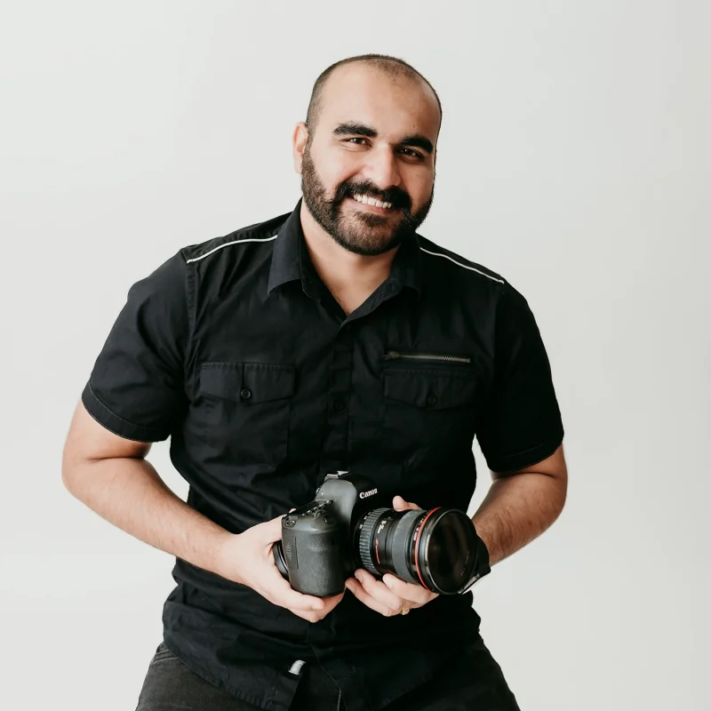 Varundeep Singh wearing black shirt owner of 'Pixel Square' holding a black canon DSLR in hand